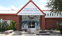 The outside of the Garcia Center, a 1-story red brick building with red trim and a peaked roof