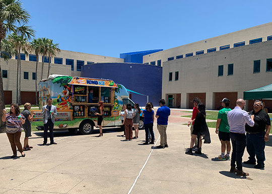 Summer 2023 break in the day: staff gathered around an ice cream truck enjoying popsicle 