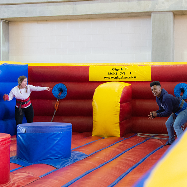A male and female student compete in a bounce house