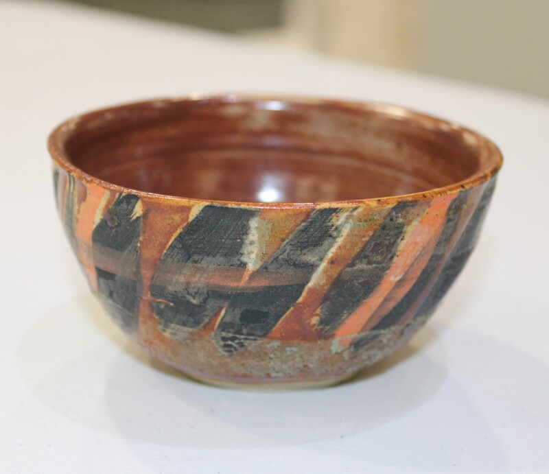 Ceramic bowl with diagonal stripe pattern in brown, gray, and orange.