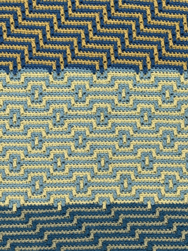 Artist: Lisa Louis. 60 by 40-inch mosaic crochet afghan. Afghan crocheted in intricate geometric patterns in hues of green and blue.