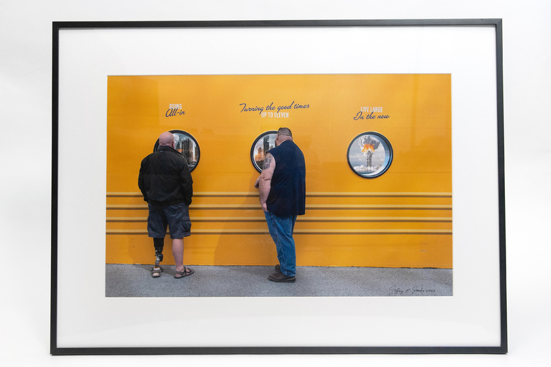 Two people looking into portholes on a yellow wall.