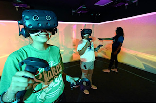 Three students in the immersive reality lab on campus 2022-2023. They are using the VR headsets