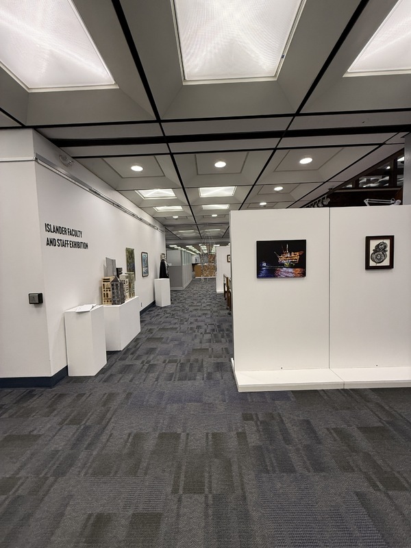 Art exhibition space with various artworks on walls, pedestals, and tables.