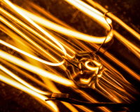 Close up photograph of the glowing filaments of a light bulb. The fixture is angled in the frame from bottom right to upper left corner.
