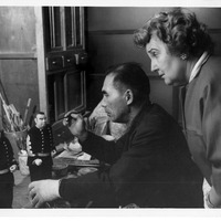 Man painting a figurine with a woman observing in an art workshop.