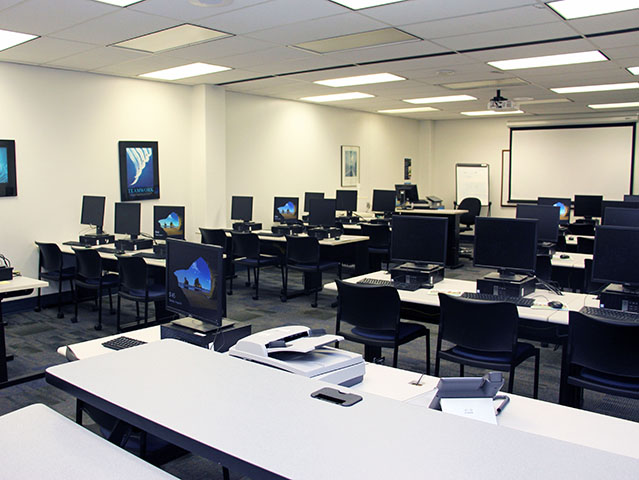 Computer lab 1 showing rows of computers, tables, and chairs with projector and screen