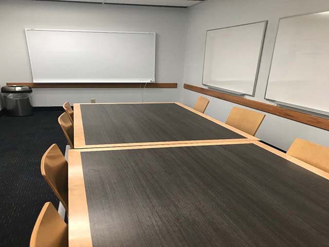 Large study room with two white boards, tables, chairs, and smart board