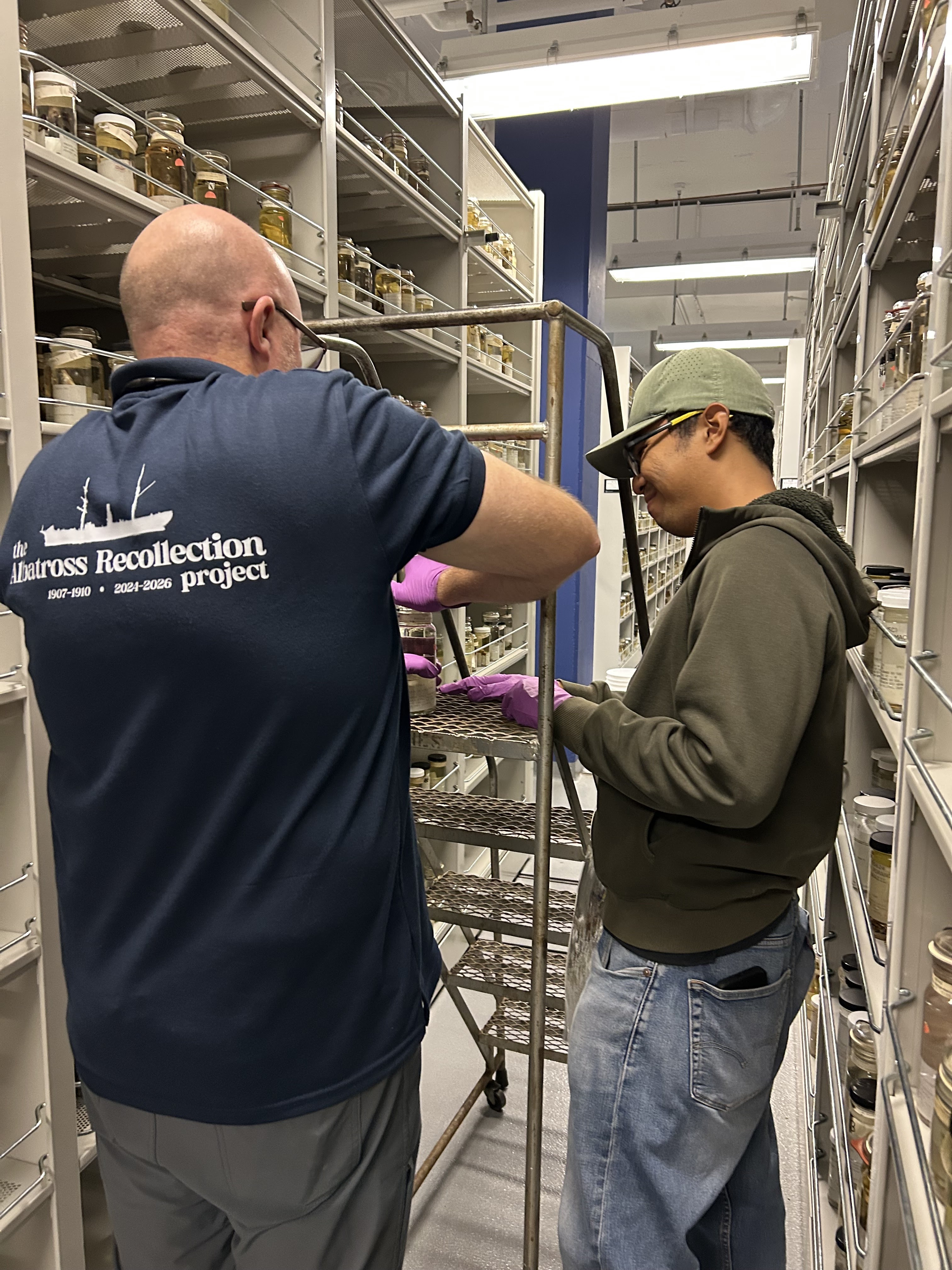 researchers standing next to shelves of jars of fish