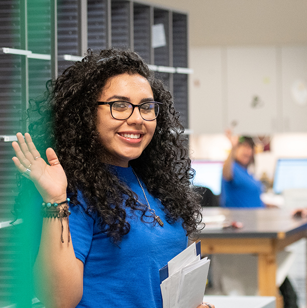 Female student waving in her blue shirt