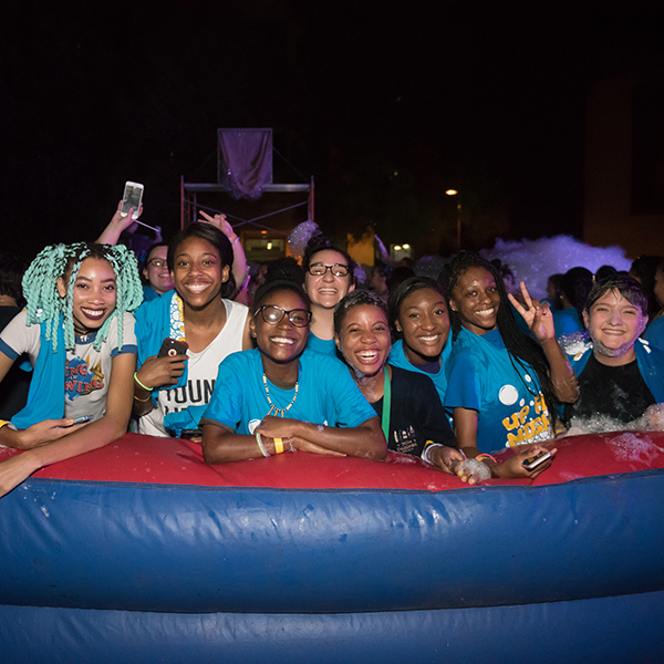 Students gather in an inflatable at night covered in foam