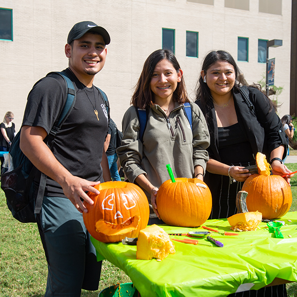 # students smile as they carve pumpkins