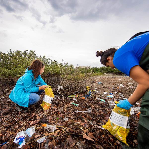 Two girls pick up trash in the marshes